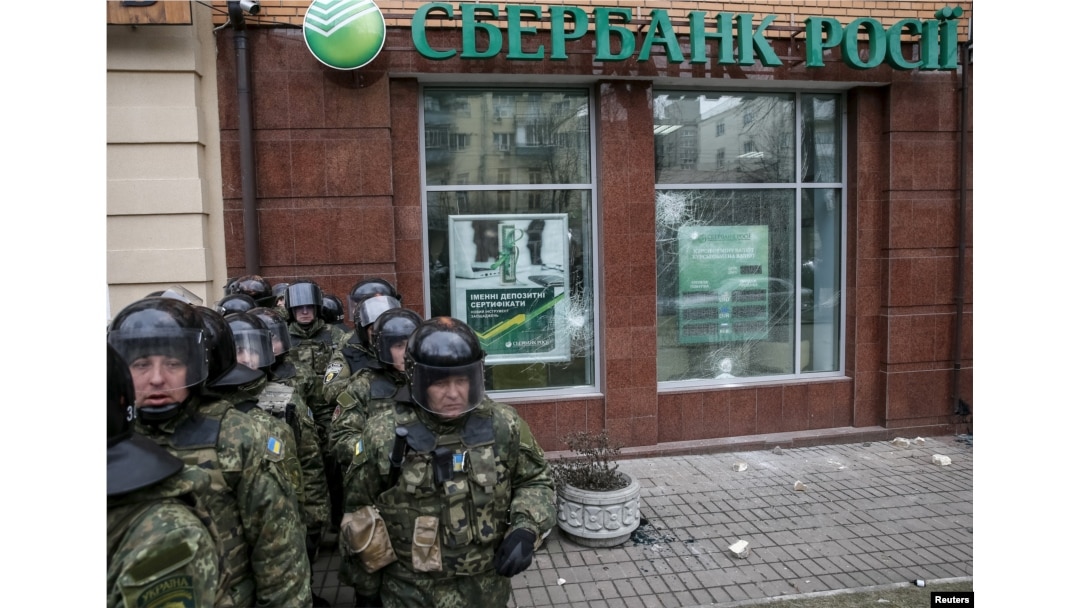 Interior Ministry security force members stand guard outside a branch of Russian bank Sberbank, which was attacked during a protest against Russia in Kiev, Ukraine, Feb. 20, 2016.