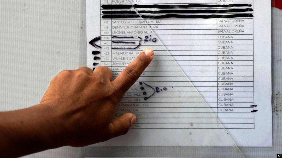 FILE - A migrant in Matamoros, Mexico checks a typewritten list of more than 800 people seeking asylum in the US, April 30, 2019. Those marked with the word "rio," Spanish for river, are believed to have crossed the Rio Grande to enter the US without authorization.