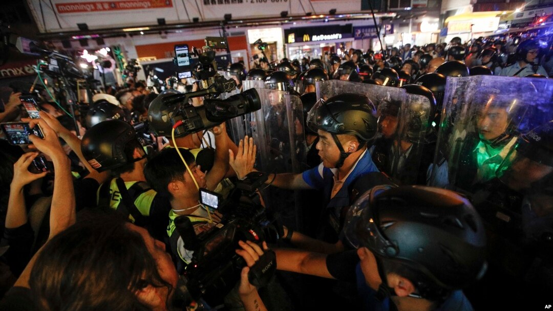 Journalists film policemen clearing a street in Hong Kong, July 7, 2019.