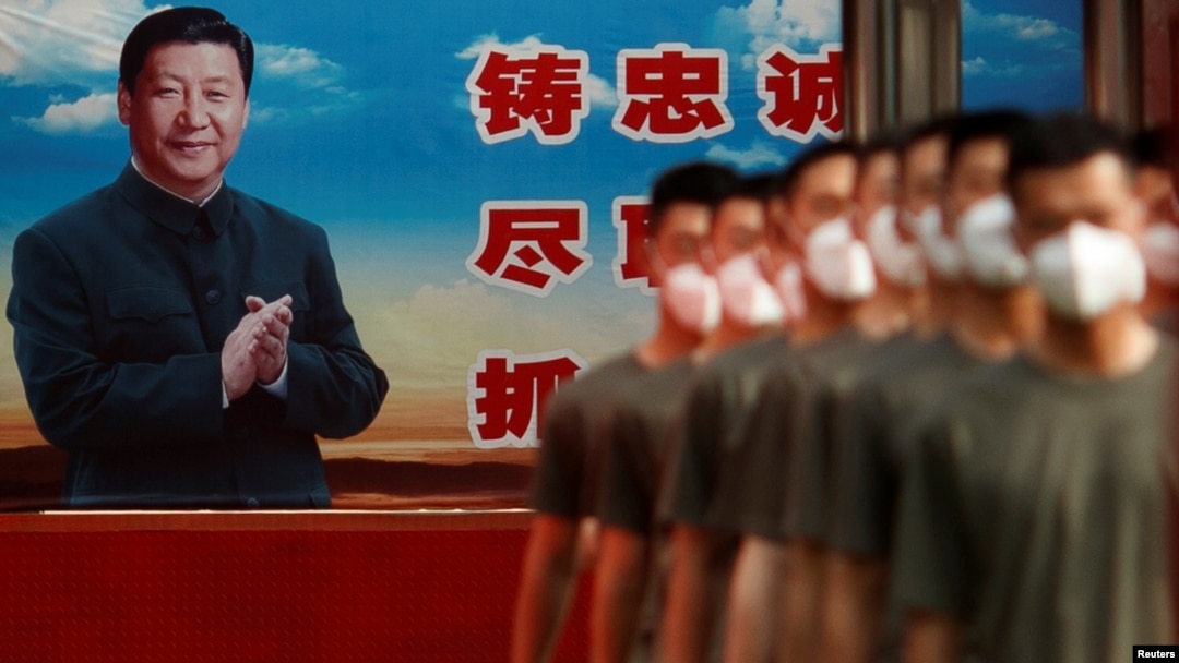 FILE - Paramilitary police officers march in formation near a poster of Chinese President Xi Jinping at the gate to the Forbidden City, in Beijing, China, May 22, 2020.