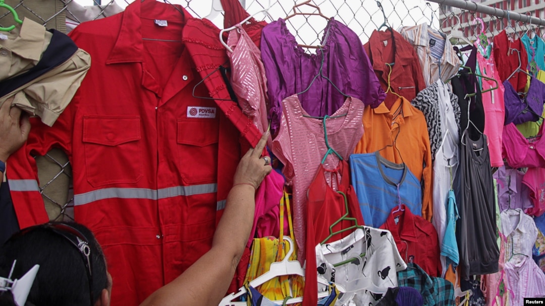 FILE -- A customer looks at PDVSA overalls for sale at a market in Maracaibo, Venezuela, Sept. 11, 2016.