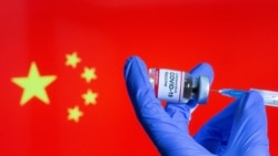 中国国旗前贴有新冠病毒疫苗标签的小瓶子