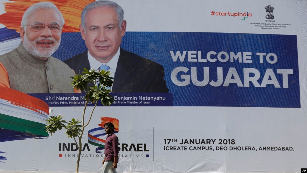 An Indian man walks past a hoarding put up to welcome Israeli Prime Minister Benjamin Netanyahu that features him along with Indian Prime Minister Narendra Modi at the International Centre for Entrepreneurship and Technology (iCreate) near Bavla in Ahmada
