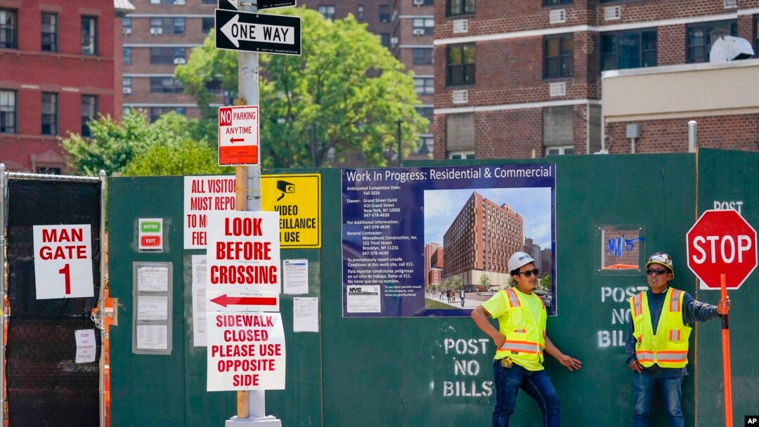 Construction workers help direct traffic outside a residential and commercial building under construction on the Lower East Side of Manhattan, as hiring boom continued last month, Aug 4, 2022. 