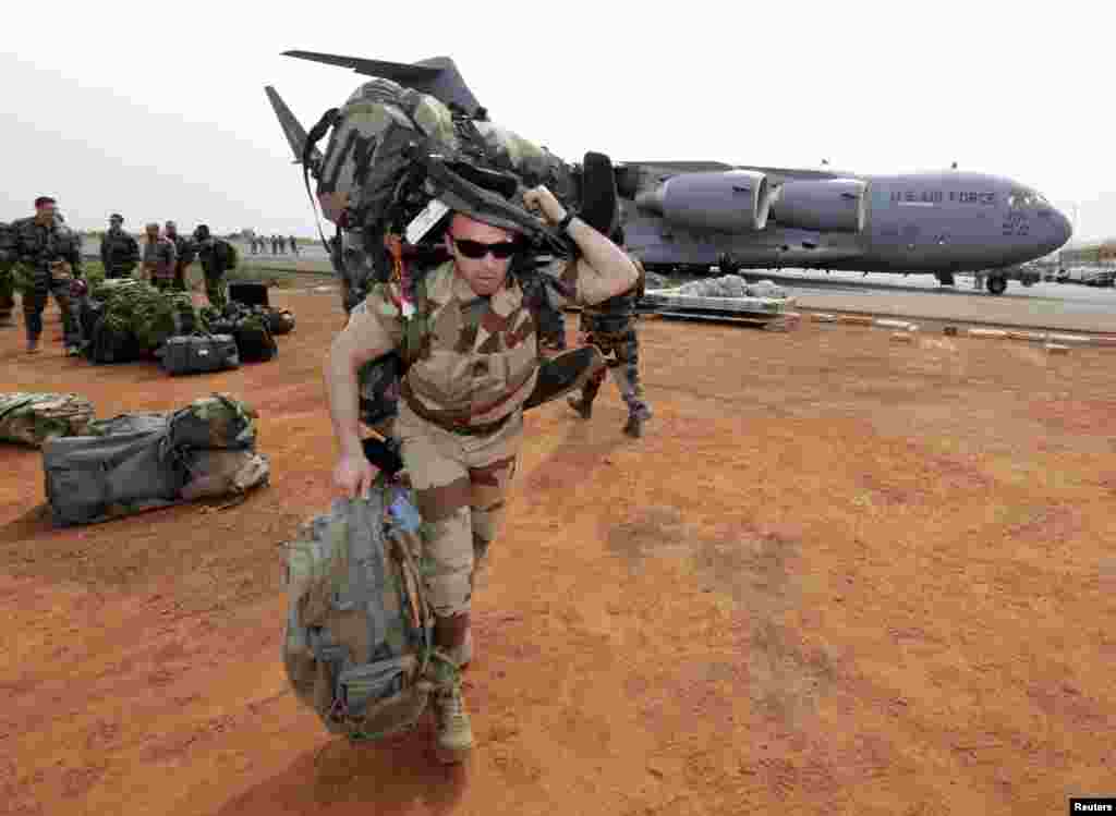 A French soldier carries his equipment after arriving on a US Air Force C-17 transport plane at the airport in Bamako, Mali, January 22, 2013.