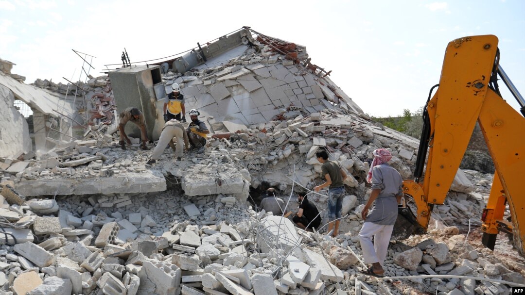Members of the Syrian Civil Defense (White Helmets) search for victims amidst the rubble of a building that collapsed during reported airstrikes by pro-regime forces in the village of Beinin in the northern Idlib province, Aug. 20, 2019. 