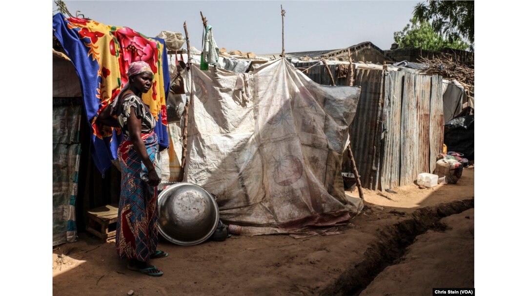 FILE - A woman stands outside a makeshift house at an internally displaced persons camp in Maiduguri, Nigeria, March 24, 2016.