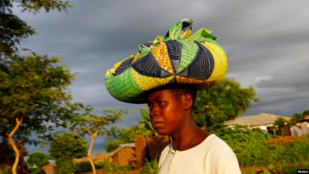 Rain clouds loom as Malawian subsistence farmer Louise Abele carries maize she has bought to feed her family near the capital Lilongwe, Malawi, Jan. 31, 2016. 
