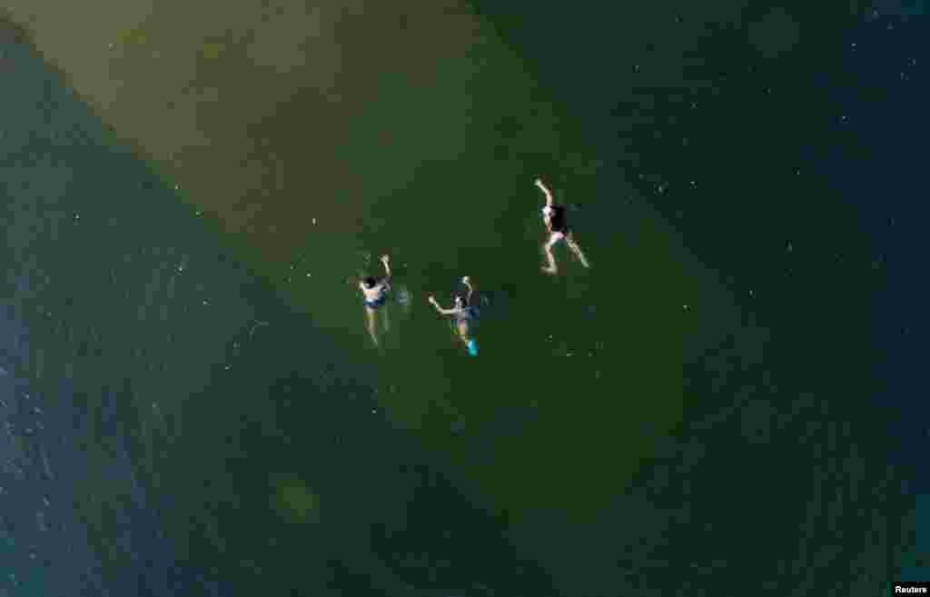 An aerial view shows youths swimming in the Yenisei River on a hot summer day, with the air temperature at about 30 degrees Celsius (86 degrees Fahrenheit), outside Krasnoyarsk, Russia.