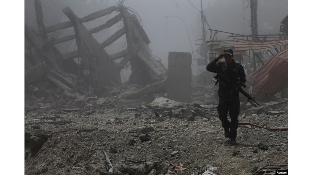 FILE - A member of Iraqi federal police walks past the debris of buildings destroyed in clashes in the Old City of Mosul, Iraq July 10, 2017.