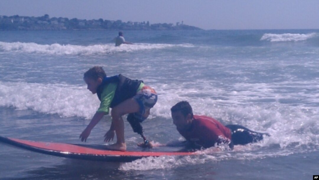 Shaun McLaughlin, 6, who was born without a right foot, gives surfing a try under the watchful eye of AmpSurf volunteers and instructors.
