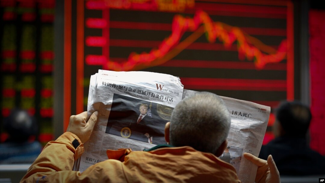 A man reads a newspaper reporting a story of U.S. President Donald Trump opening conditional dialogue with North Korean leader Kim Jong Un, at a brokerage house in Beijing, Jan. 8, 2017. Trade between China and North Korea fell 50 percent in December.