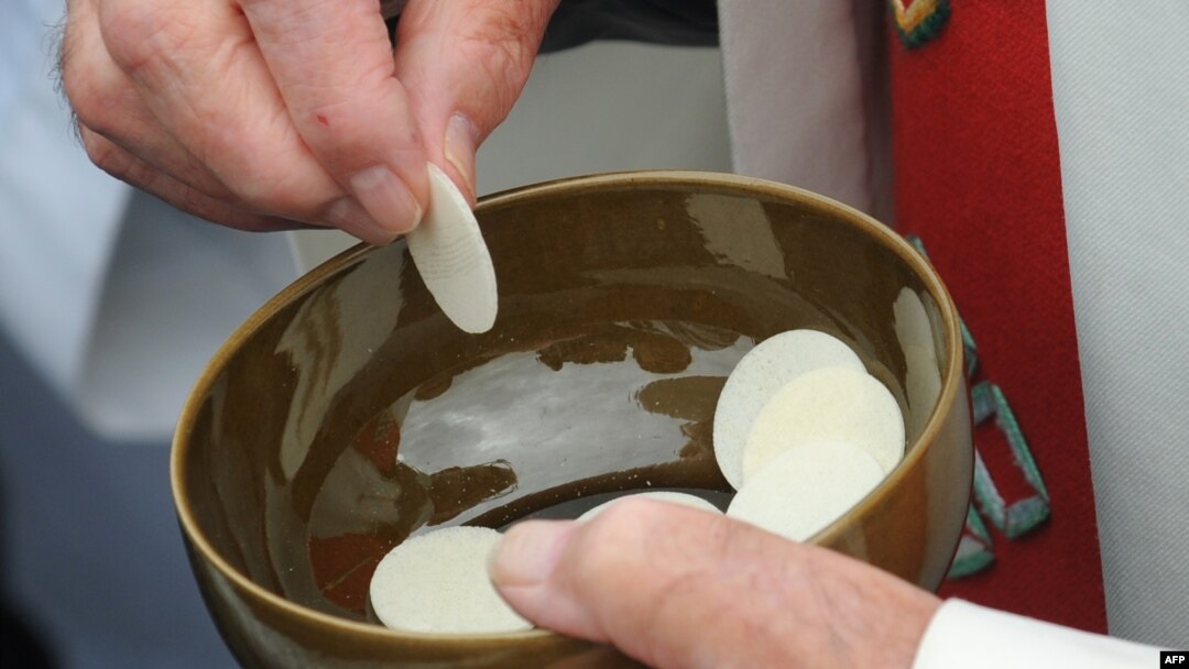 FILE - A priests holds communion wafers after a mass at La Prairie in Lourdes, Sept. 14, 2008.