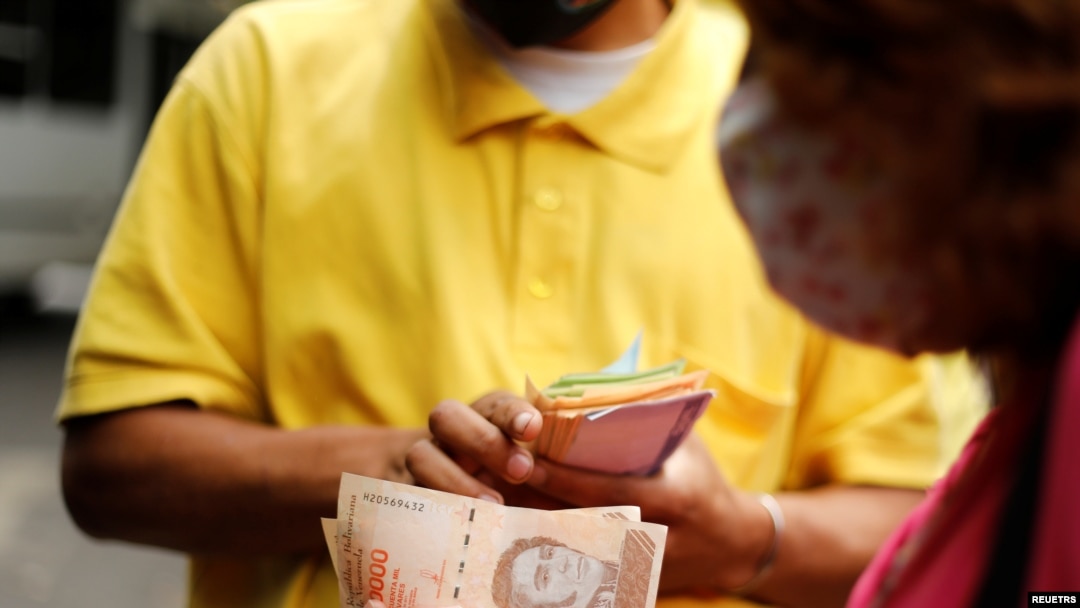 Una mujer paga un pasaje de bus con billetes de 50.000 bolívares, solo 2,5 centavos de dólar cada uno al tipo de cambio del momento, en Caracas. Marzo 16, 2021.