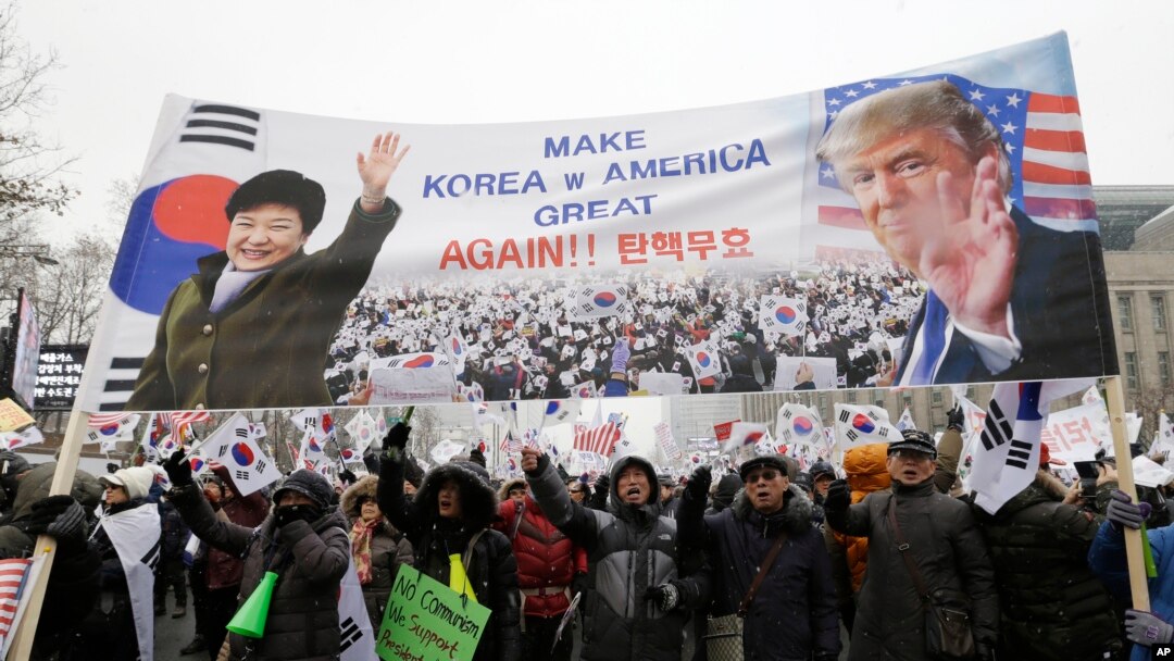 A banner showing pictures of impeached South Korean President Park Geun-hye and U.S. President Donald Trump is displayed as supporters of Park wave flags of the United States and South Korea during a rally opposing her impeachment in Seoul, South Korea,