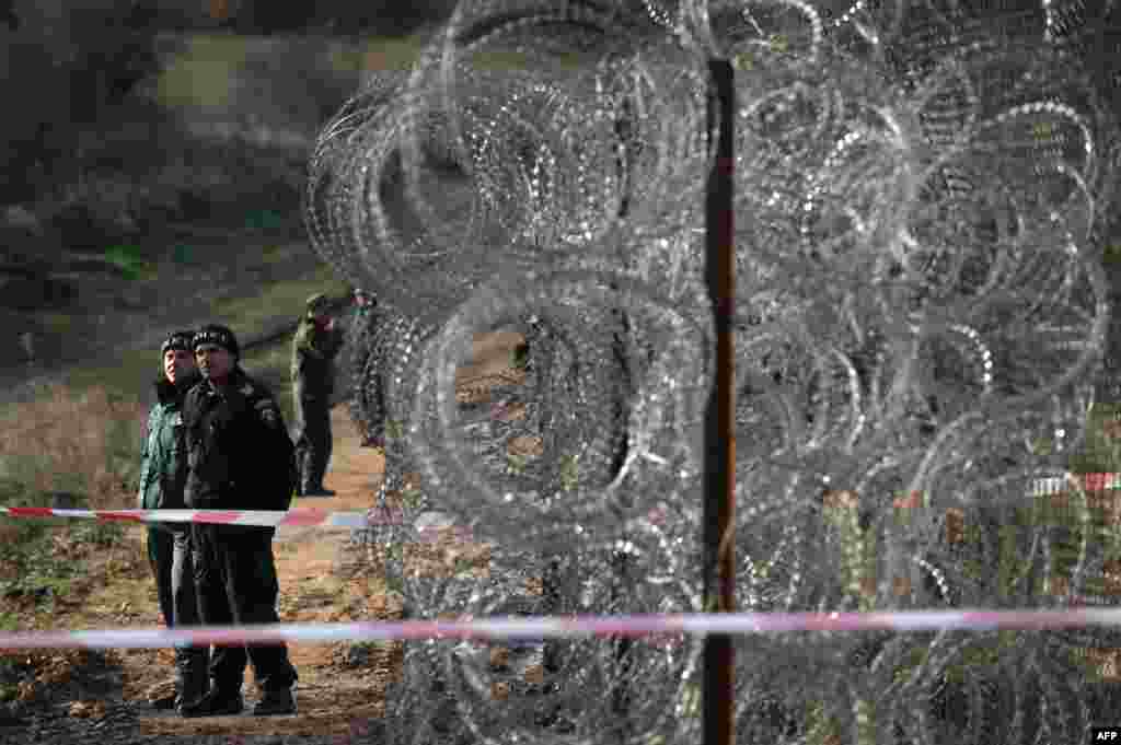 Border police stand guard next to a border fence being built on the Bulgarian border with Turkey, near the village of Golyam Dervent. Bulgaria, the European Union's poorest member, has been overwhelmed by the arrival this year of almost 10,000 refugees, 60 percent of them Syrians fleeing civil war crossing over illegally from Turkey.
