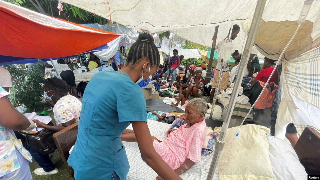A woman is attended to by a member of the medical personnel outside a hospital after Saturday's 7.2 magnitude quake, in Les Cayes, Haiti, August 16, 2021.