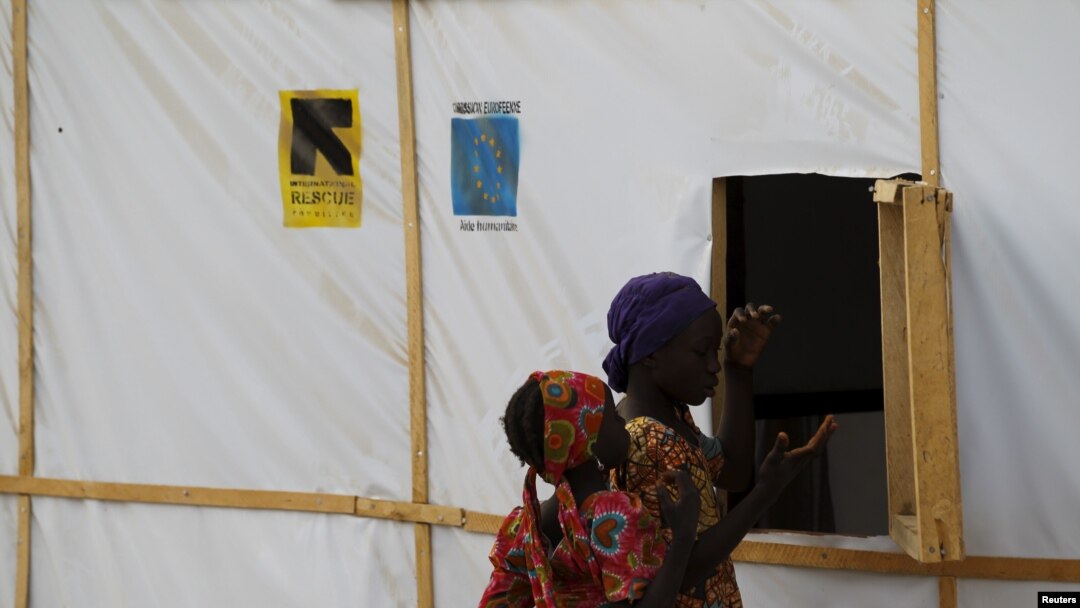 FILE - A woman and a girl are seen outside makeshift accommodations at camp for internally displaced people in Maiduguri, Nigeria, March 8, 2016.