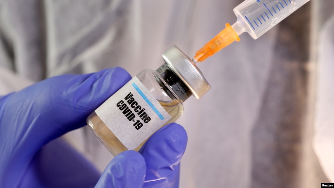 A woman holds a small bottle labbeled with a "Vaccine COVID-19" sticker and a medical syringe in this illustration taken April 10, 2020.