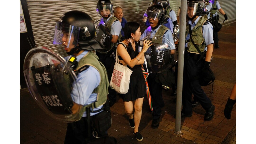 Policemen push a woman as they clear a street during a protest in Hong Kong, July 7, 2019.