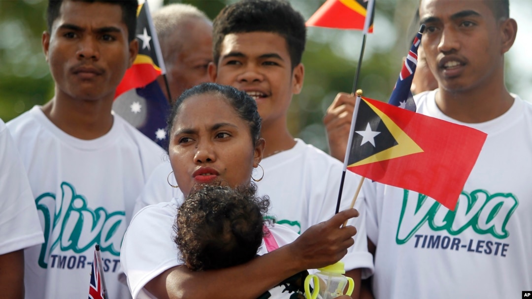 In this Friday, Aug. 30, 2019, photo, people wave East Timorese flags during the commemoration of the 20th anniversary of a referendum that secured its independence from Indonesia, in Dili, East Timor.
