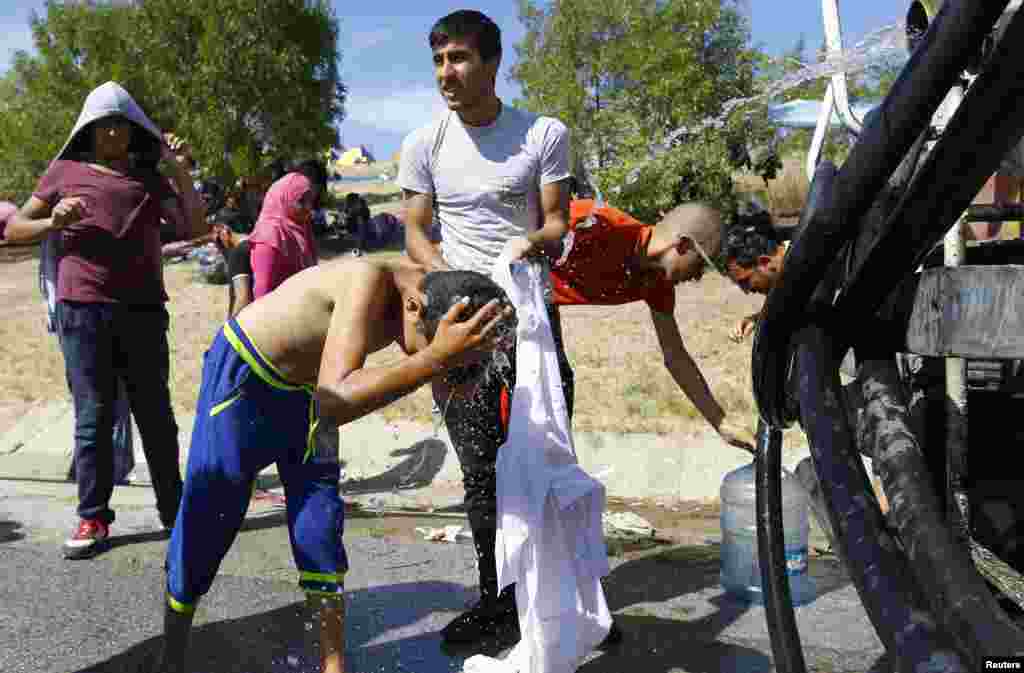 A migrant child washes his head with water on the side of a highway near Edirne, Turkey. Hundreds of migrants spent the night out in the open near Turkey's border with Greece, after Turkish police halted their bid to reach the frontier and cross into the European Union.