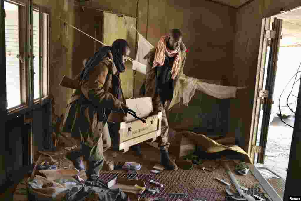 Malian soldiers carry a box of ammunition after searching through debris at a military camp in Diabaly, Mali, January 21 2013.
