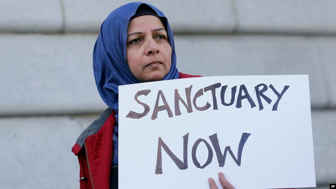 FILE - Moina Shaiq holds a sign at a rally outside of City Hall in San Francisco, Jan. 25, 2017.