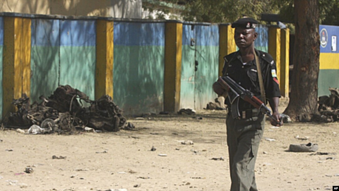 Um polícia em patrulha passa em frente ao comando da polícia de Kano, atacado pelos bombistas