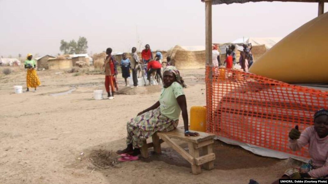 FILE - A Nigerian woman rests beside a vast water bladder at the arid Minawao refugee camp in Cameroon, Dec. 11, 2015.