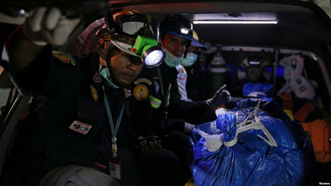 Thai rescue workers sit next to a body on a stretcher, a victim of a boat accident off the tourist island of Phuket, July 7, 2018.