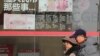 Residents walk past board highlighting the security markers on the latest Yuan note outside a bank in Beijing, China, Nov. 24, 2016.