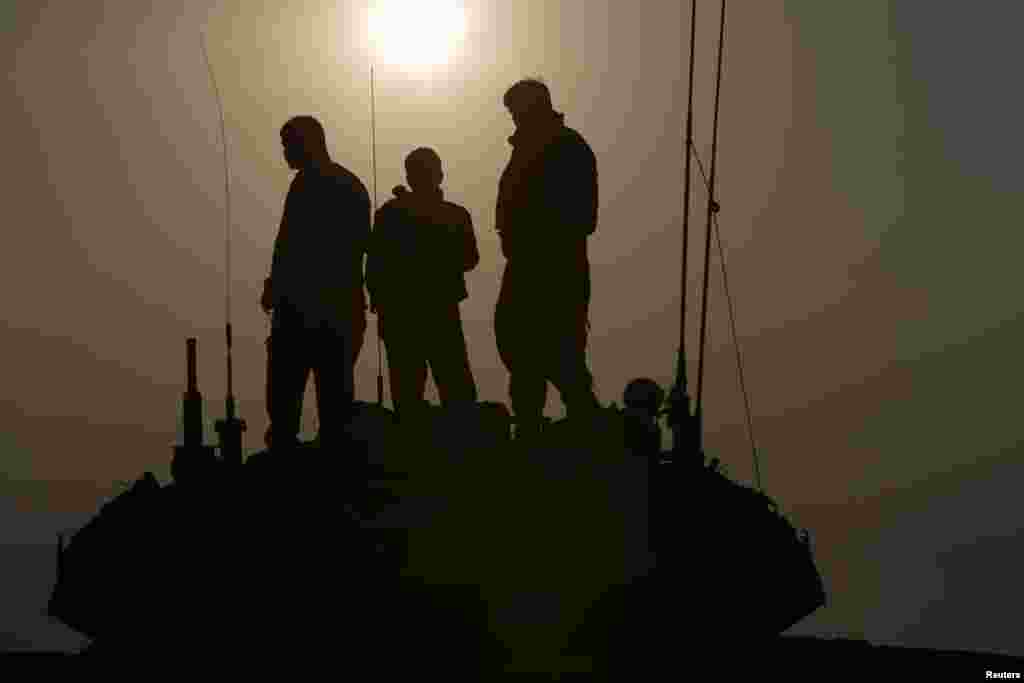 Israeli soldiers stand atop a tank near the border with Gaza, July 29, 2014.