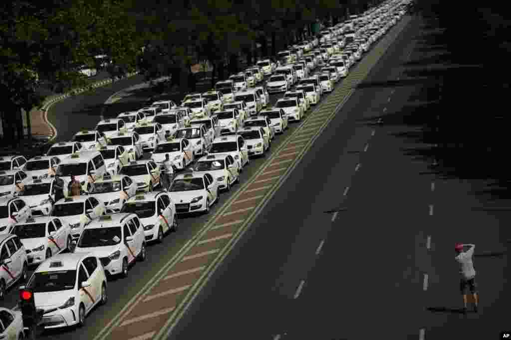 A man takes a photograph of parked taxis blocking the main Castellana avenue in Madrid. Representatives of taxi driver unions and Spain's government are meeting to find a way out of an indefinite strike protesting the proliferation of private ride-hailing services.