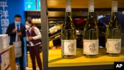 FILE - A staff member talks with a visitor near a display of Australian wines at the China International Import Expo (CIIE) in Shanghai on Nov. 5, 2020. 