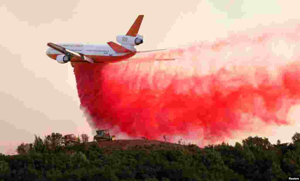 A DC-10 air tanker drops fire retardant along the crest of a hill to protect the two bulldozers below that were cutting fire lines at the River Fire (Mendocino Complex) near Lakeport, California, U.S. August 2, 2018.