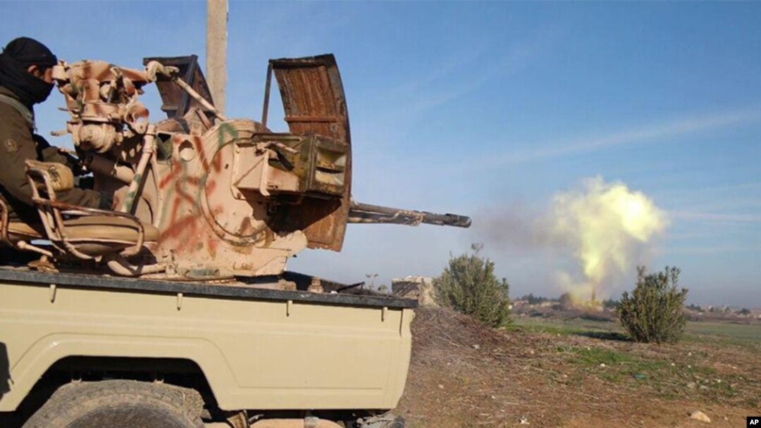 In this image posted on a militant social media account by the Al-Baraka division of the Islamic State group, Feb. 24, 2015, a fighter fires a heavy weapon mounted on the back of a pickup truck in Tal Tamr, Syria.