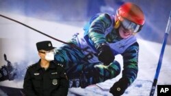 中國河北張家口火車站外一名警察站在2022北京冬奧會的廣告牆前。（美聯社2021年11月26日）