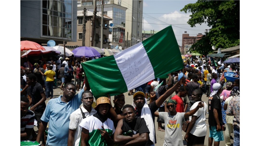 People hold banners as they demonstrate on the street to protest against police brutality, in Lagos, Nigeria, Tuesday Oct. 20, 2020. After 13 days of protests against police brutality, authorities have imposed a 24-hour curfew in Lagos Nigeria's…