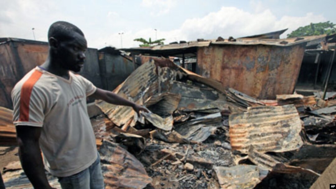 A man points to a burnt shop near Williamsville after a clash between Ivorian security forces and pro-Outtara fighters in Abidjan, March 15, 2011