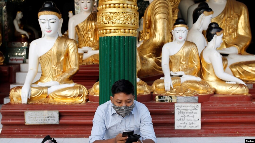 FILE - A man wears a face mask as he uses his phone at Shwedagon Pagoda in Yangon, Myanmar, Jan. 31, 2020.