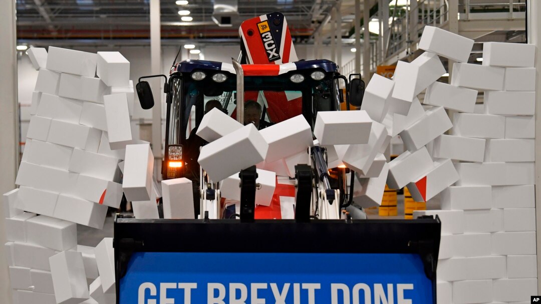 Britain's Prime Minister Boris Johnson drives a JCB through a symbolic wall with the Conservative Party slogan 'Get Brexit Done' in the digger bucket, during an election campaign event at the JCB manufacturing facility in Uttoxeter, England.