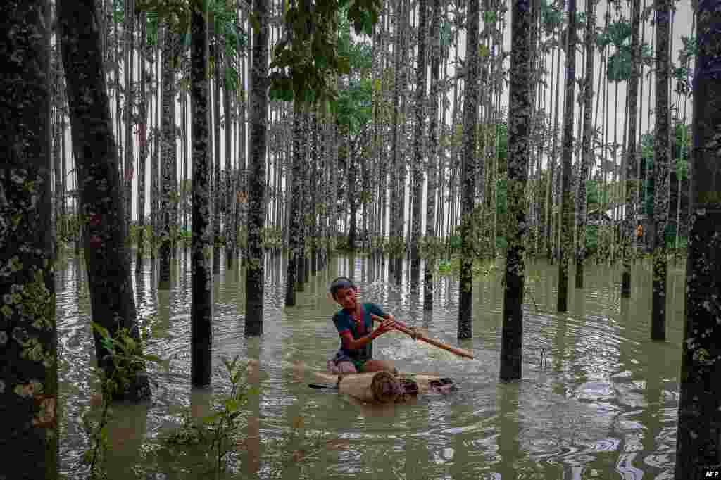 A child wades through a flooded area using a makeshift raft at Maulovir Para, Cox's Bazar, after monsoon floods and landslides cut off more than 300,000 people in villages across southeast Bangladesh and killed at least 20 people.