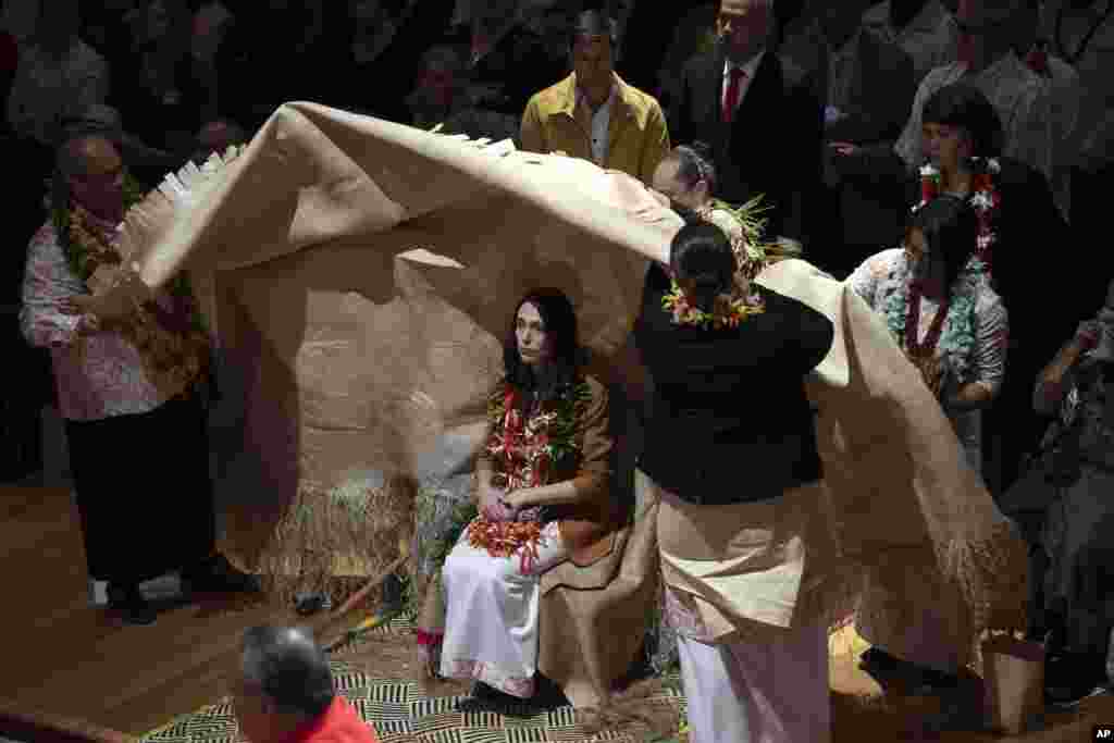 New Zealand Prime Minister Jacinda Ardern, center, is covered during a ceremony in Auckland, to formally apologize for a racially charged part of the nation's history known as the Dawn Raids.