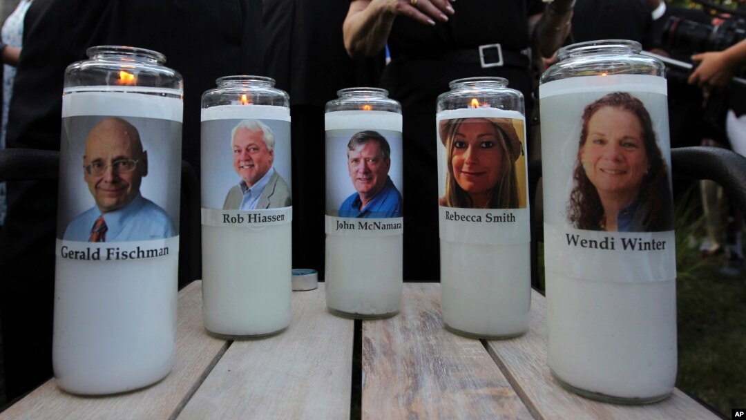 Photos of five journalists adorn candles during a vigil across the street from where they were slain in their newsroom in Annapolis, Md., June 29, 2018.