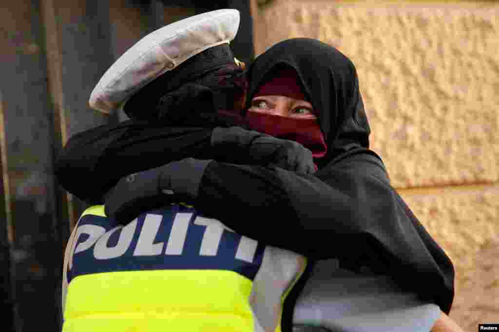 Ayah, 37, a wearer of the niqab, weeps as she is embraced by a police officer during a demonstration against the Danish face veil ban in Copenhagen, Denmark, Aug. 1, 2018.