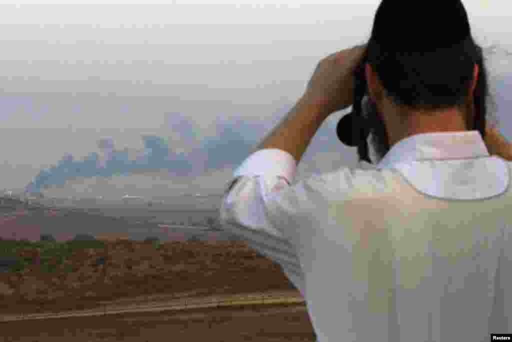 An Israeli man looks through binoculars towards the Gaza Strip near the southern town of Sderot, July 29, 2014.