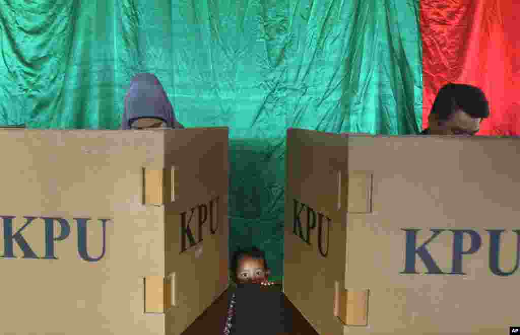 A young girl waits as her parents vote at a polling station during the parliamentary election in Banda Aceh, Indonesia, April 9, 2014.