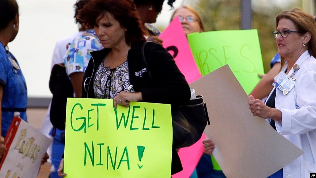 A Texas Health Presbyterian Hospital Dallas staff carries a sign wishing Nina Pham well as she and others wait for an ambulance carrying Pham to depart for Maryland, October16, 2014.