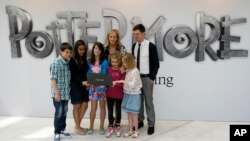 FILE - British author J.K. Rowling, center back, poses for photographers with participants during a photo call for her new website project Pottermore at the Victoria and Albert Museum in London, June 23, 2011. 
